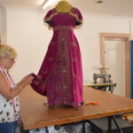 An image of costumier at The Costume Workshop adjusting a dress costume.
